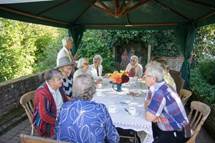 A group of people sitting at a table with a blue umbrella